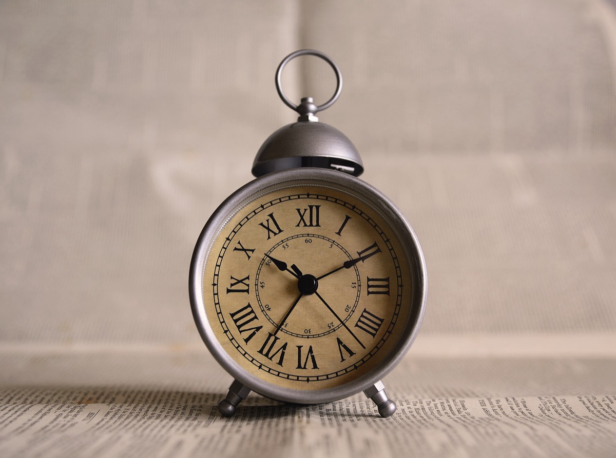 An antique alarm clock with Roman numerals around the dial and a smaller inner ring of minute numbers